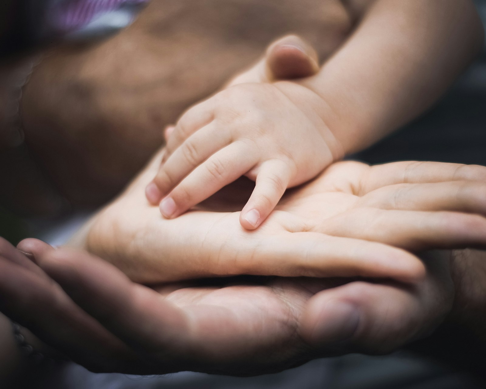 Manos de un bebé sobre las palmas de sus padres