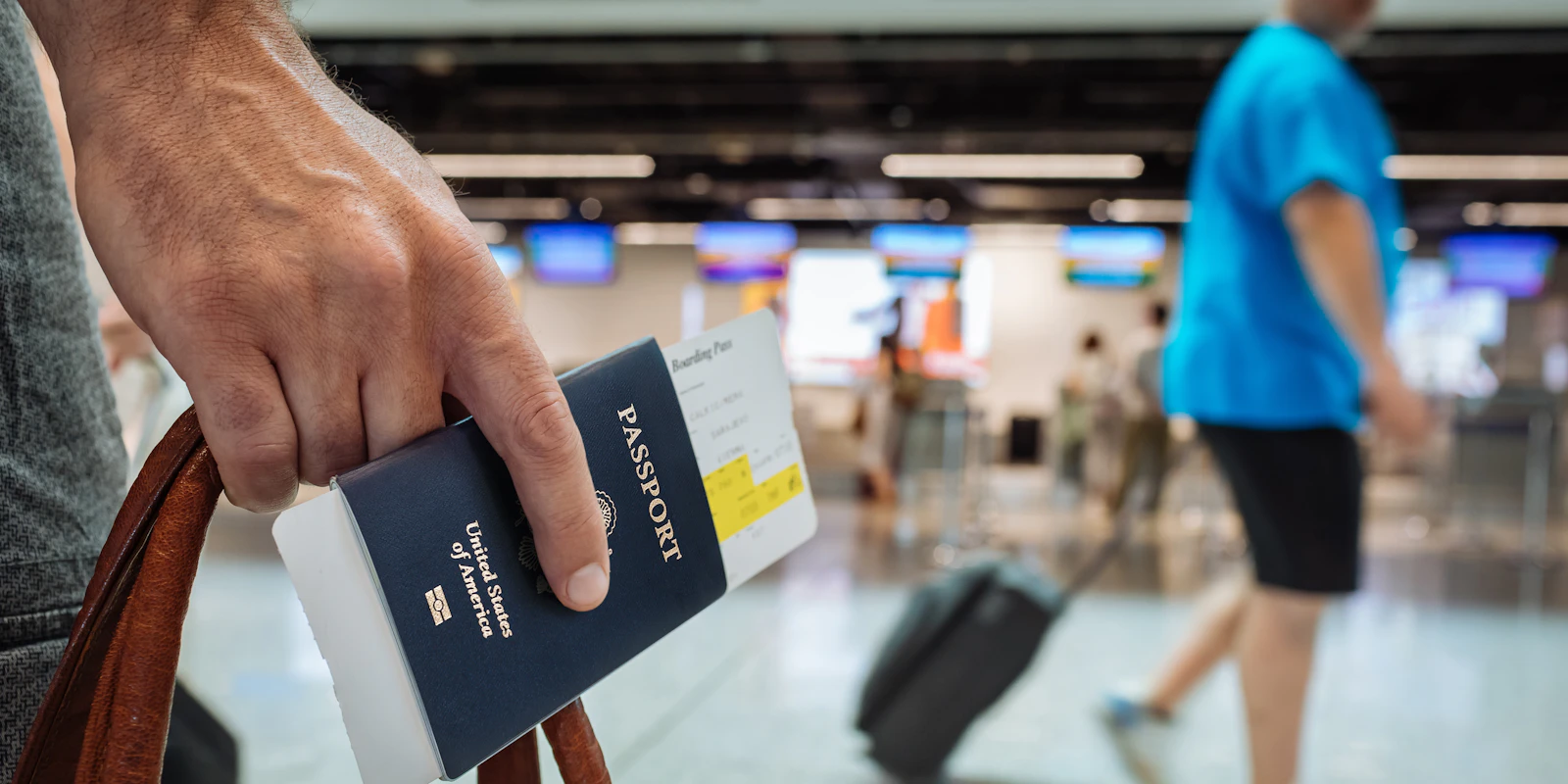 Mano sosteniendo un pasaporte en un aeropuerto